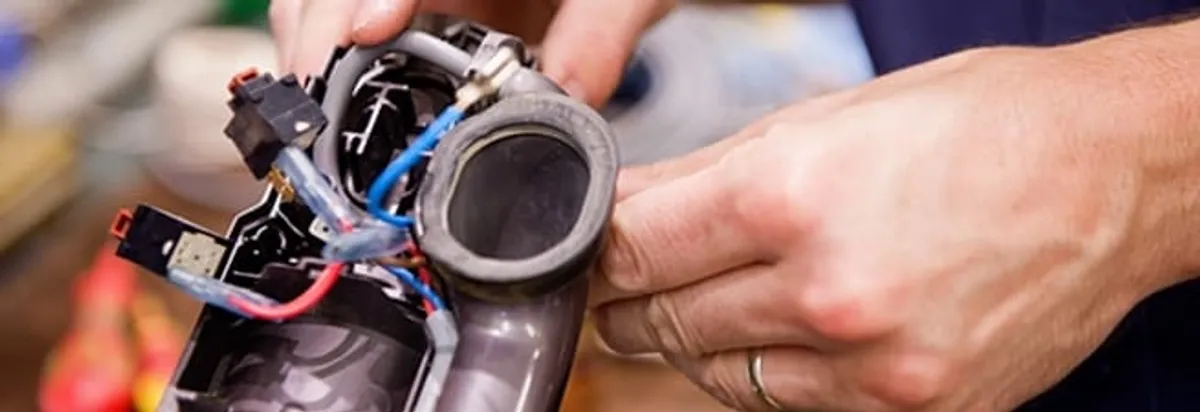 Vacuum repair technician reconnecting wiring and components in Erie, PA